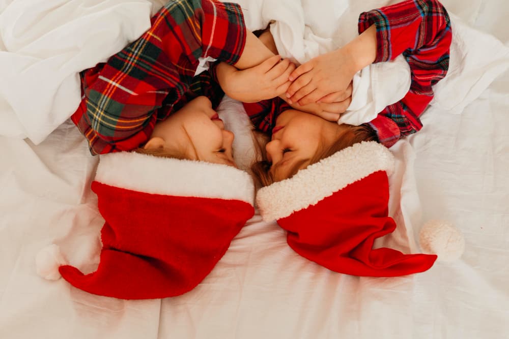 Two children are wearing Christmas pajamas
