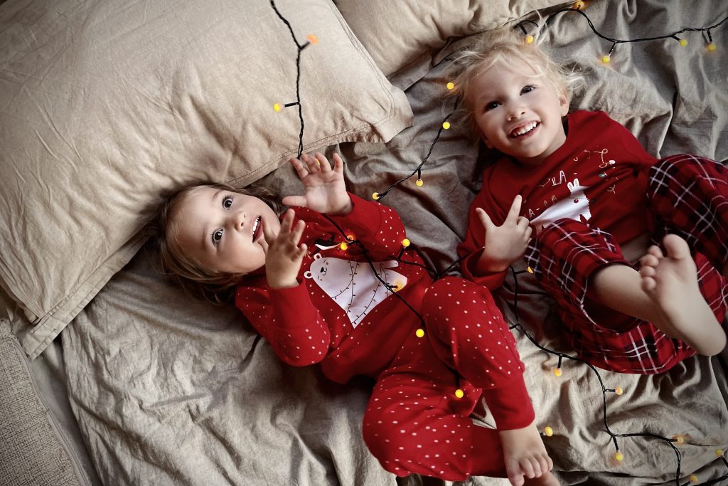 Two children are wearing Christmas pajamas