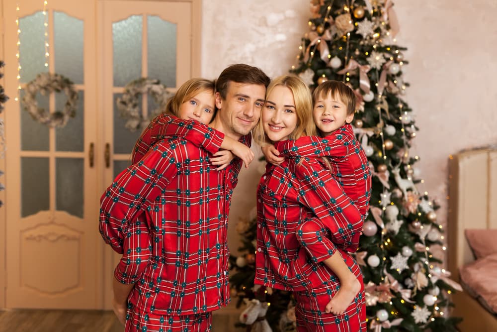 A family playing happily in red and green plaid family Christmas pajamas